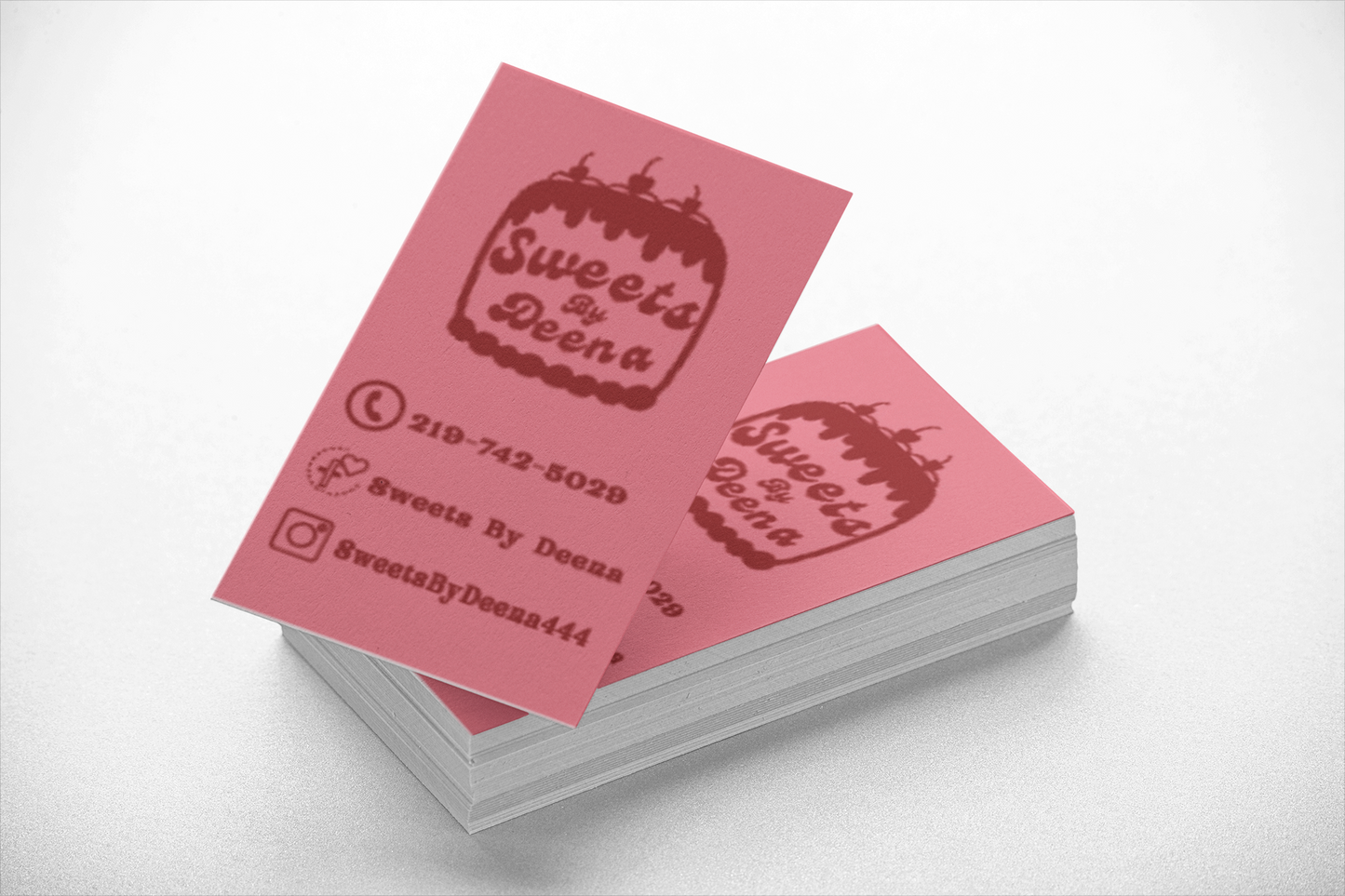 Stack of pink business cards with 'Sweets by Deena' branding on a white background